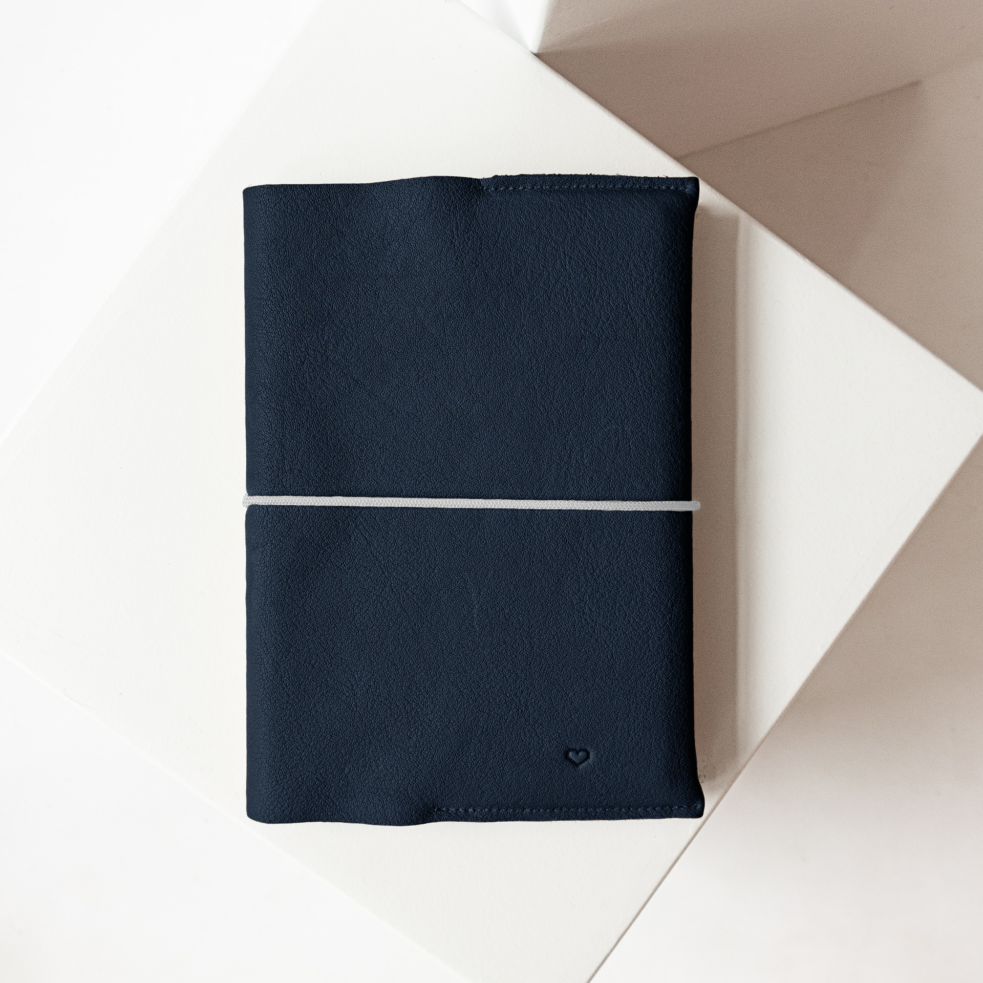 U-Hefthülle EVE aus nachhaltigem Naturleder in Dunkelblau mit schlichter Herz-Prägung und grauem Verschlussband