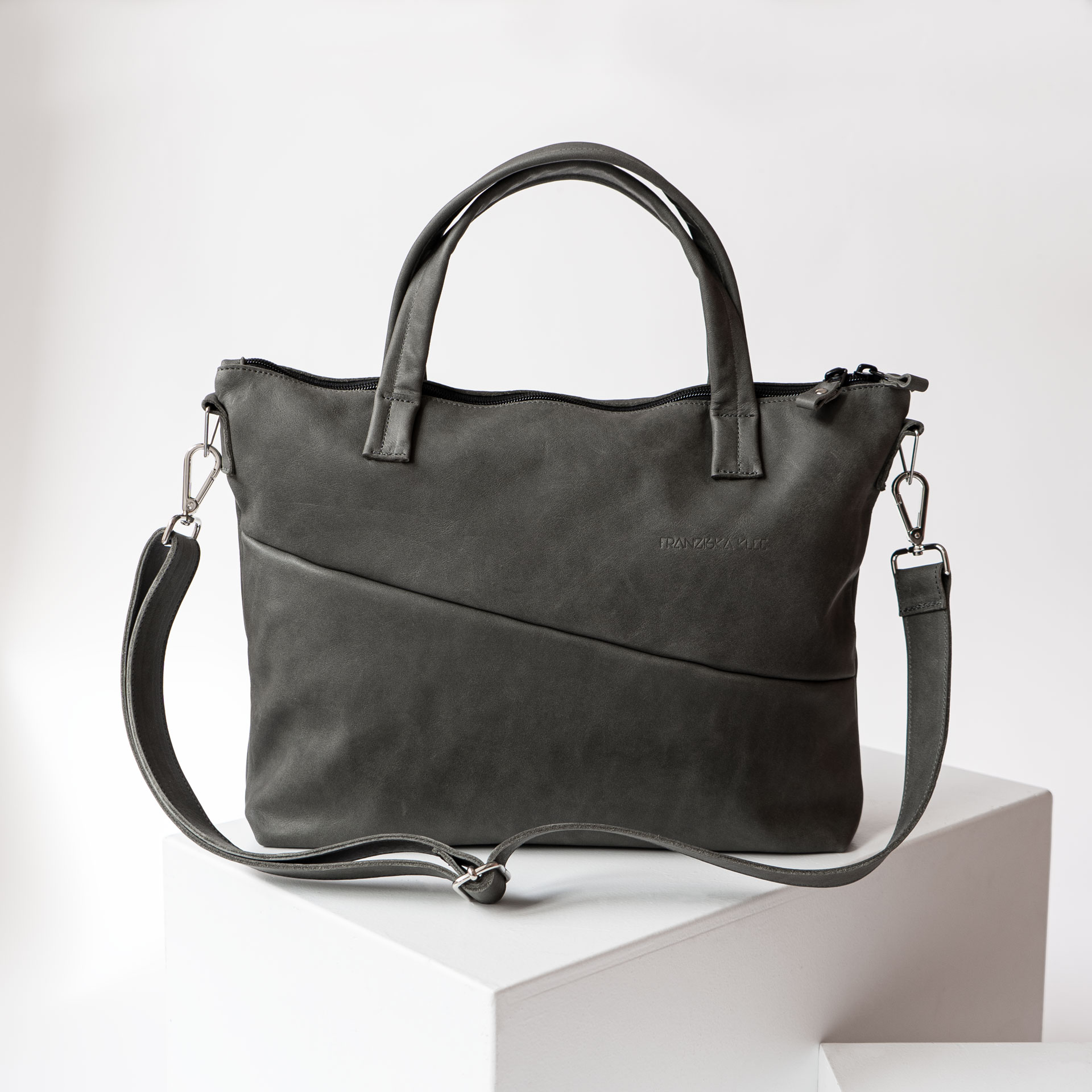 Vorderseite der Umhängetasche ANA aus nachhaltigem Naturleder in Steingrau mit verstellbarem Träger und dezenter Logoprägung