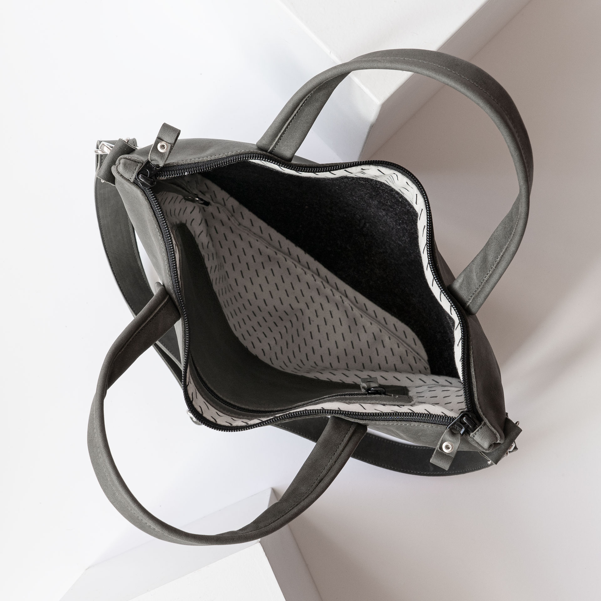 Innenansicht der Umhängetasche ANA in Steingrau mit Futterstoff, Laptopfach und kleinem Reißverschlussfach innen