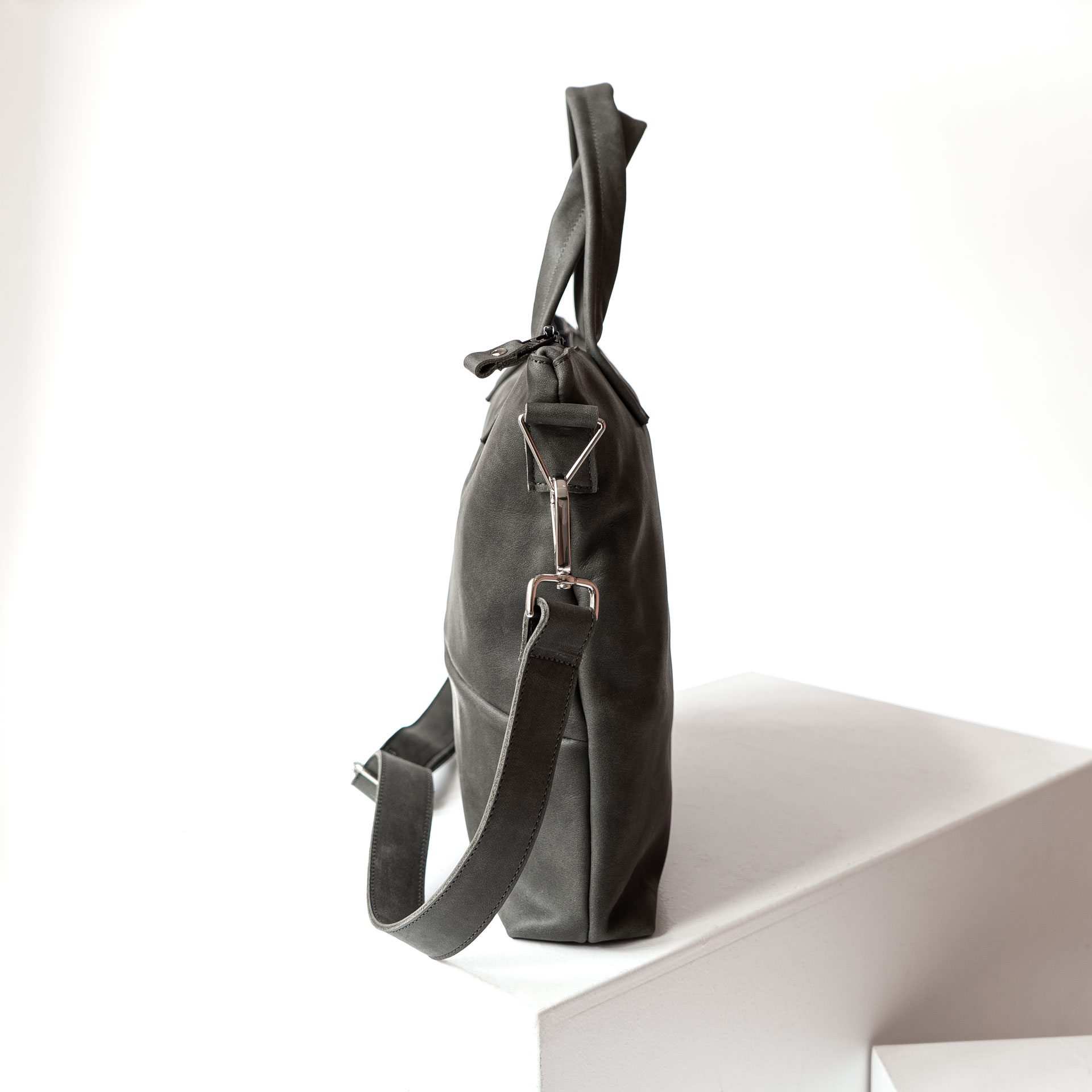 Seitenansicht der Umhängetasche ANA aus Naturleder in Steingrau mit abnehmbarem Träger und Henkeln